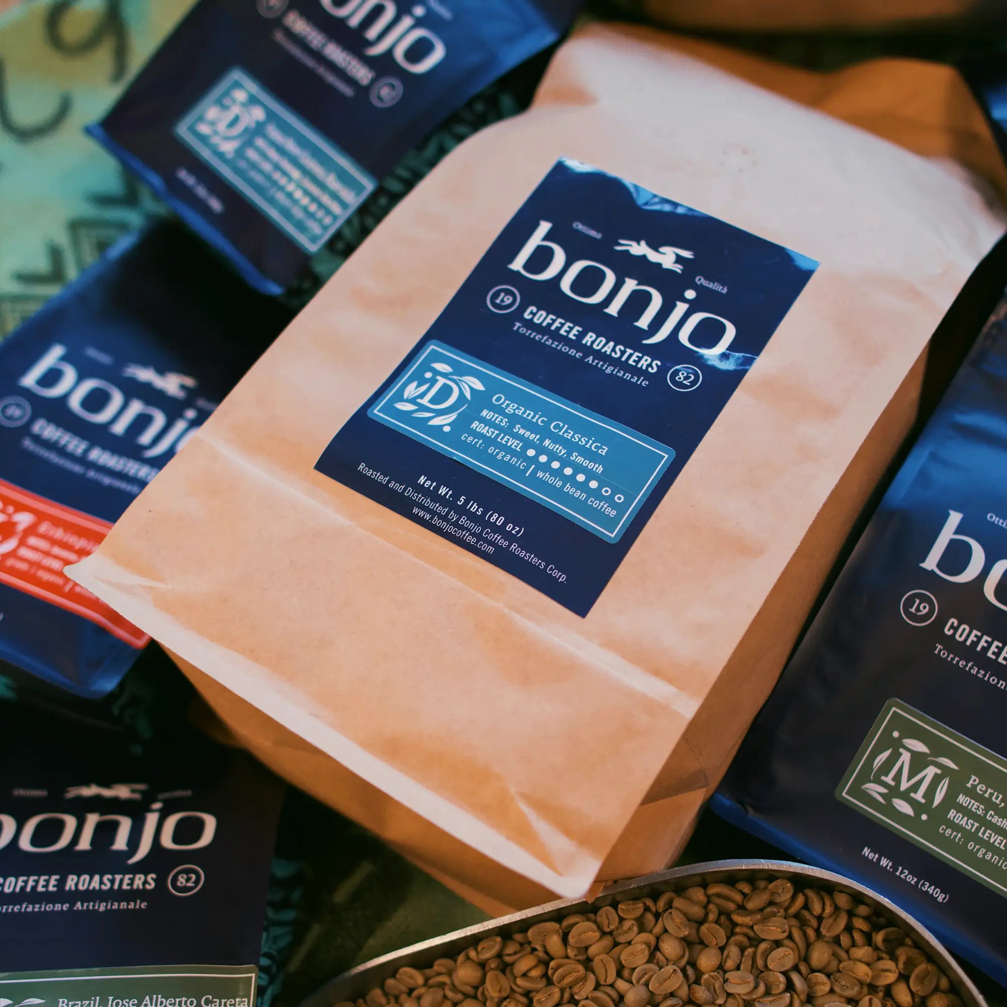 Bags of Bonjo Coffee, featuring blue labels with "Organic Classica" blend highlighted. Whole beans are visible, suggesting freshness and quality.