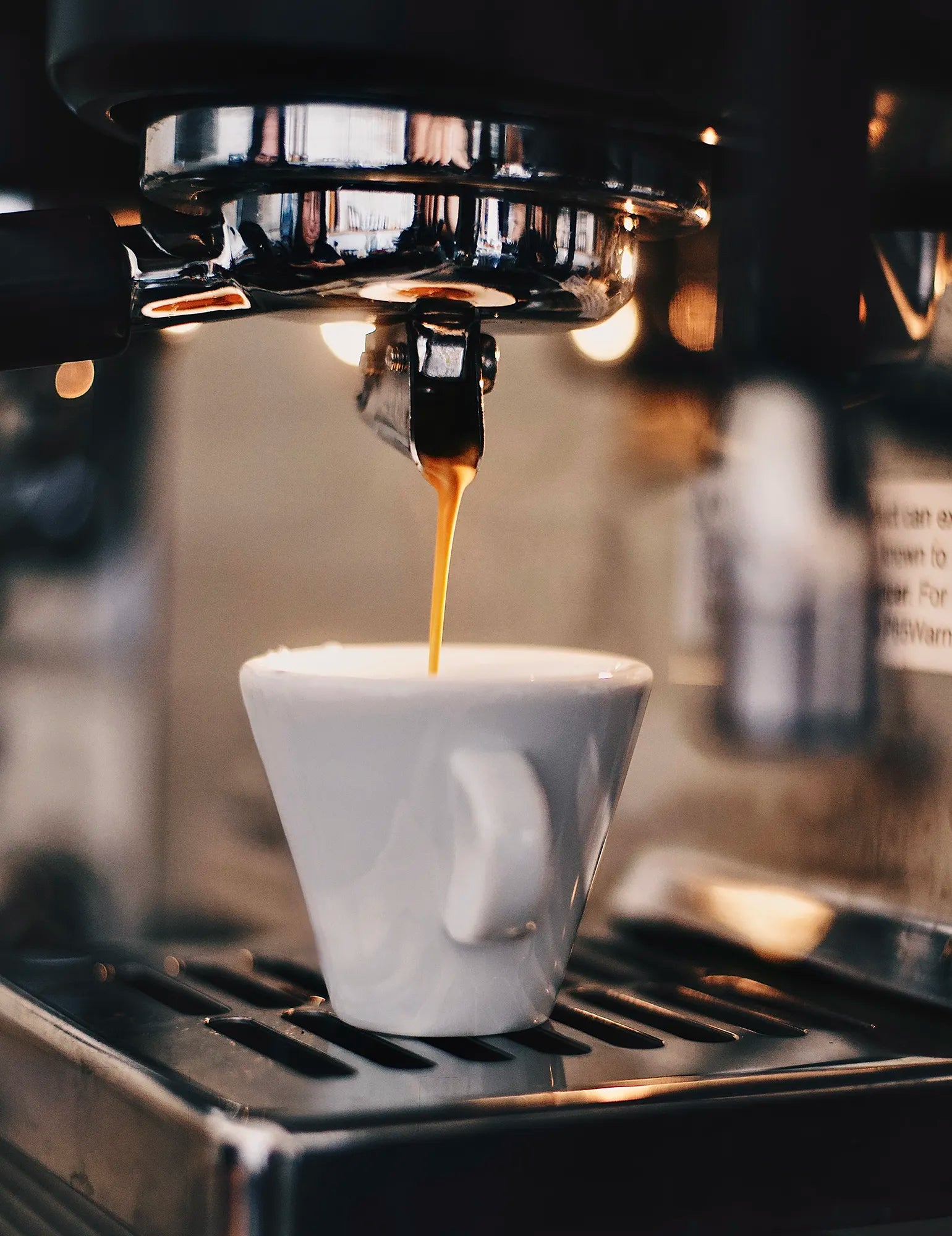 Espresso being brewed into a white cup from an espresso machine.