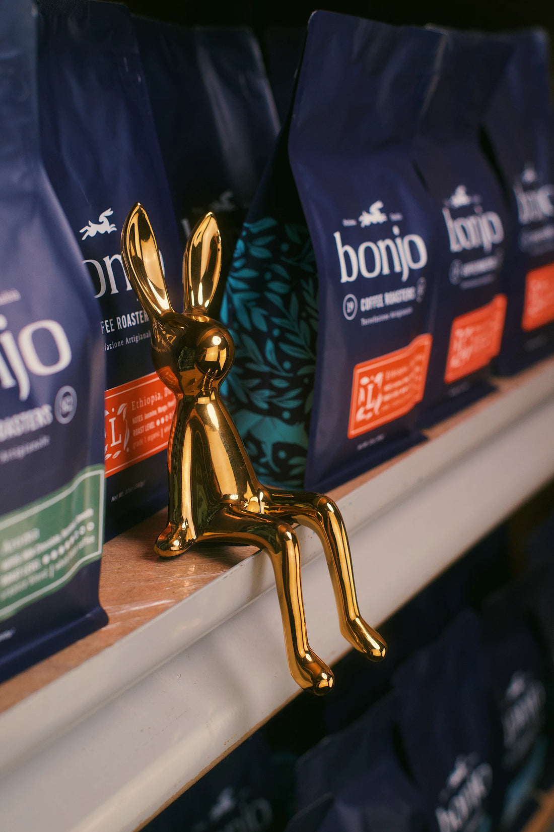 Gold rabbit-shaped object on a shelf with bonjo coffee bags in the background