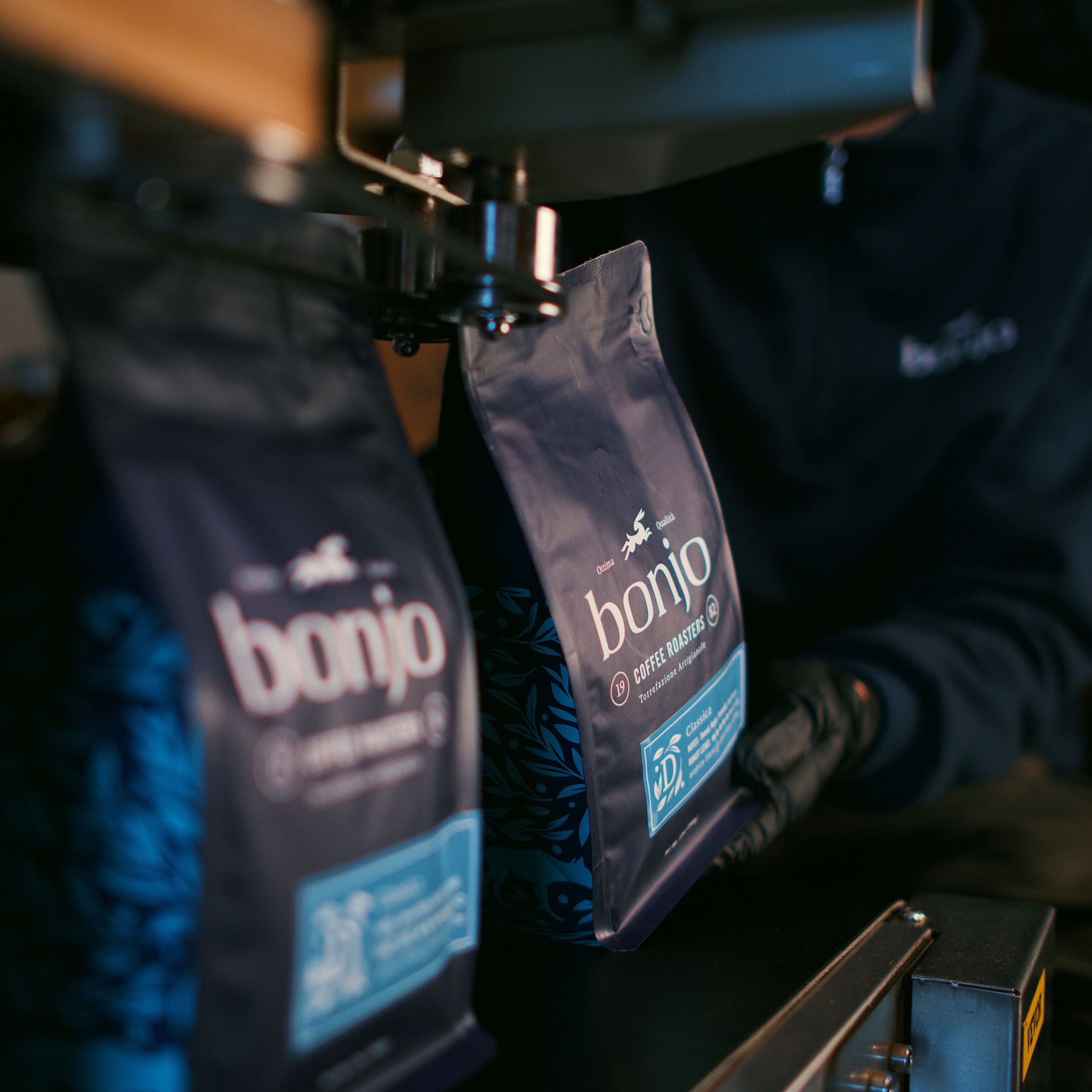 Two 'bonjo' coffee bags on a coffee machine with a person operating it.