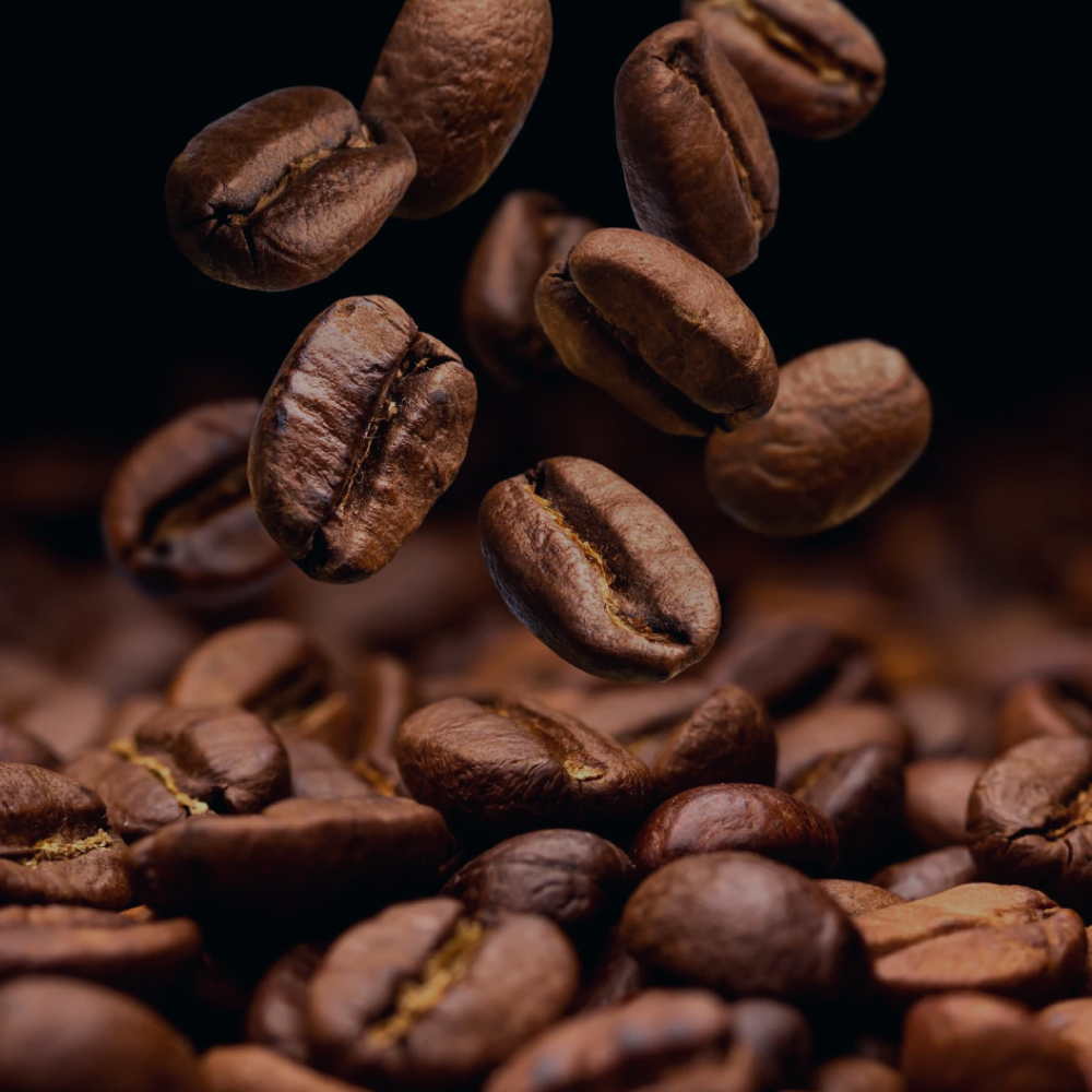 Roasted coffee beans in mid-air with a dark background